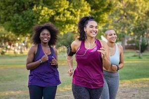 Group of three women outside walking or jogging, happy to workout.